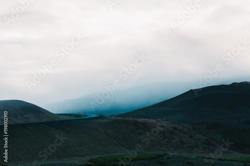 majestic icelandic landscape with hills and asphalt road at cloudy day