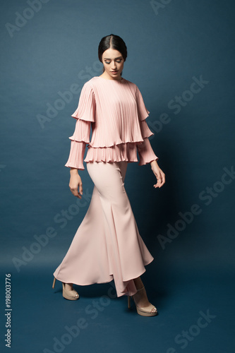 Attractive caucasian female model wearing elegant dress for work or dinner with blue background.Studio shot.