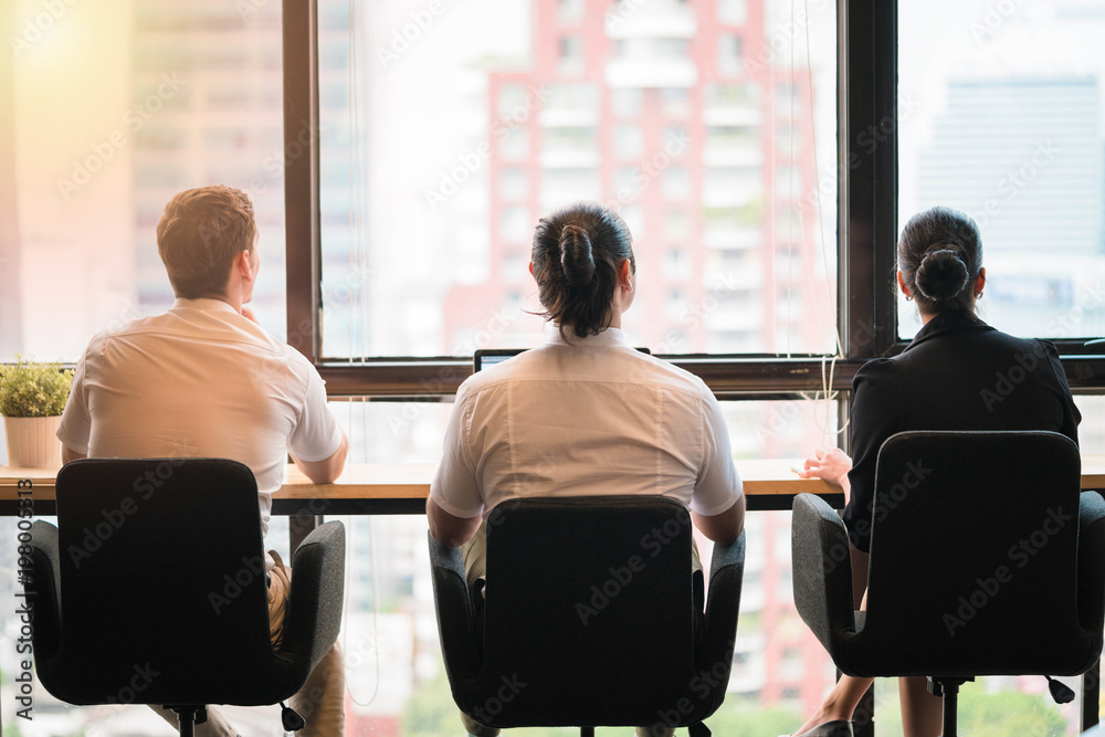 Fototapeta premium Three business people looking though window