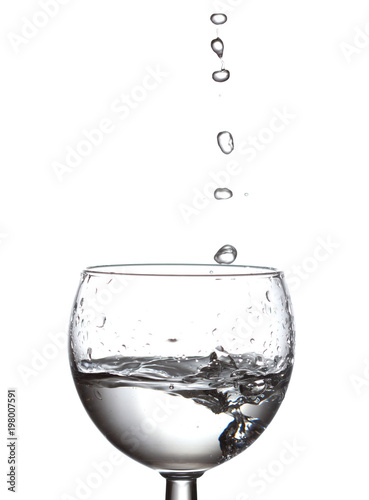 Drops of water falling in a glass. Crystal clear water, splash and bubbles of liquid on a white background. macro view shallow depth of field