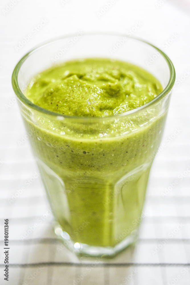 Glass with green smoothie on the kitchen table. Glass with green smoothie on the kitchen table.