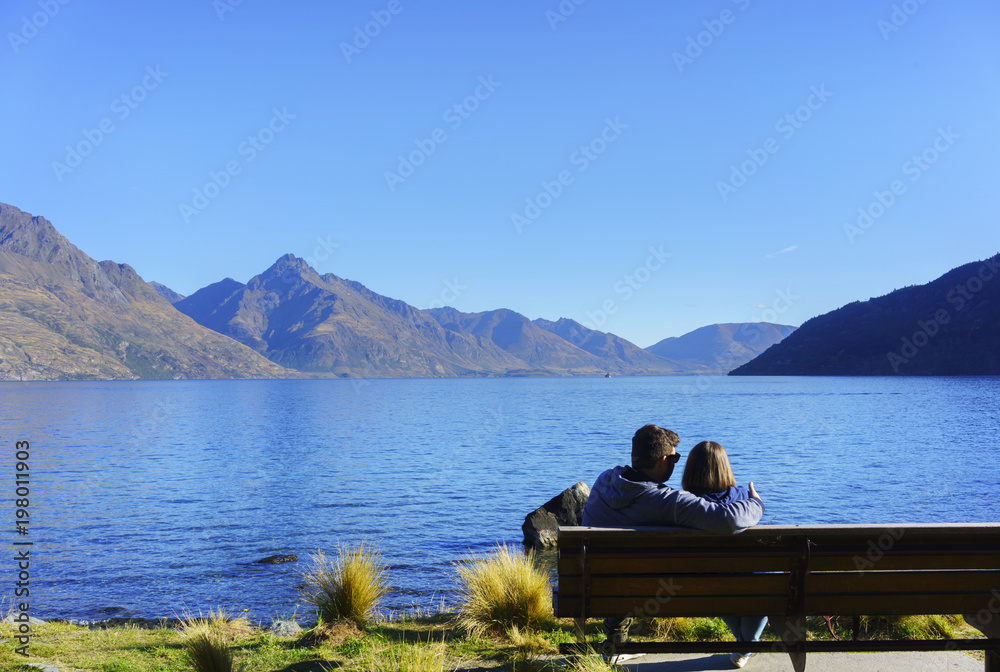 Couple sitting on the chair in Queenstown Garden , relaxing with atmosphere of Lake Wakatipu in Autumn , Queenstown , South Island of New Zealand