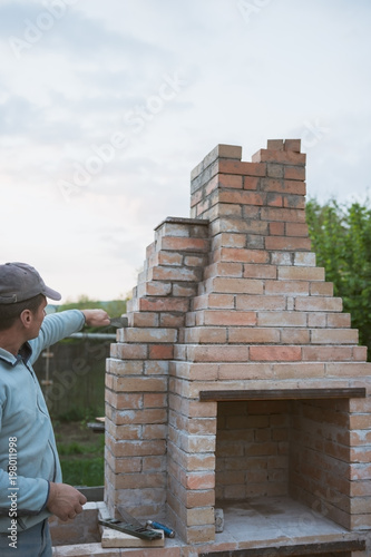 Adult man builds a brick oven
