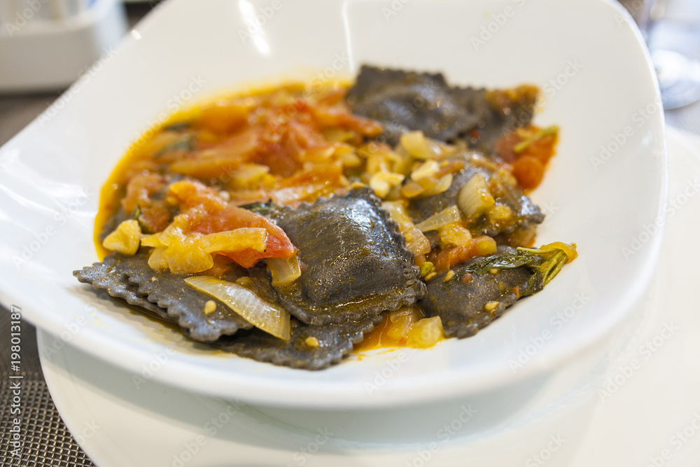 Black squid ink ravioli with natural tomatoes sauce Black squid ink ravioli with natural tomatoes sauce