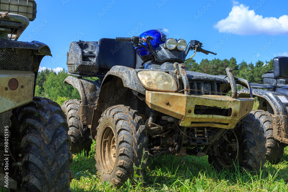 Group of young people riding ATV on dirt track Group of young people riding ATV on dirt track