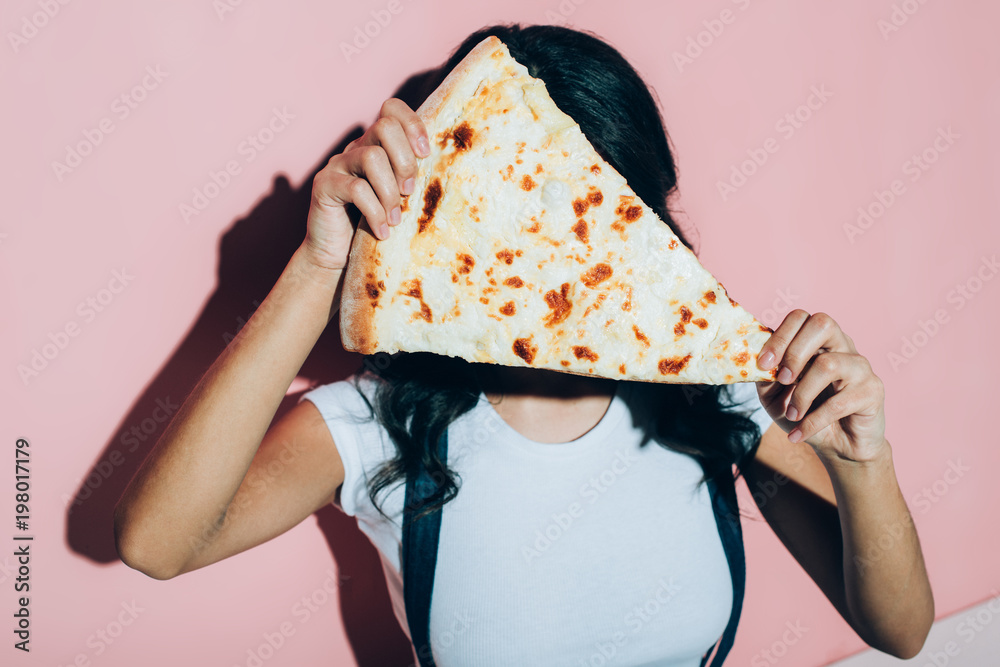 Φωτογραφία obscured view of woman covering face with piece of pizza on pink background