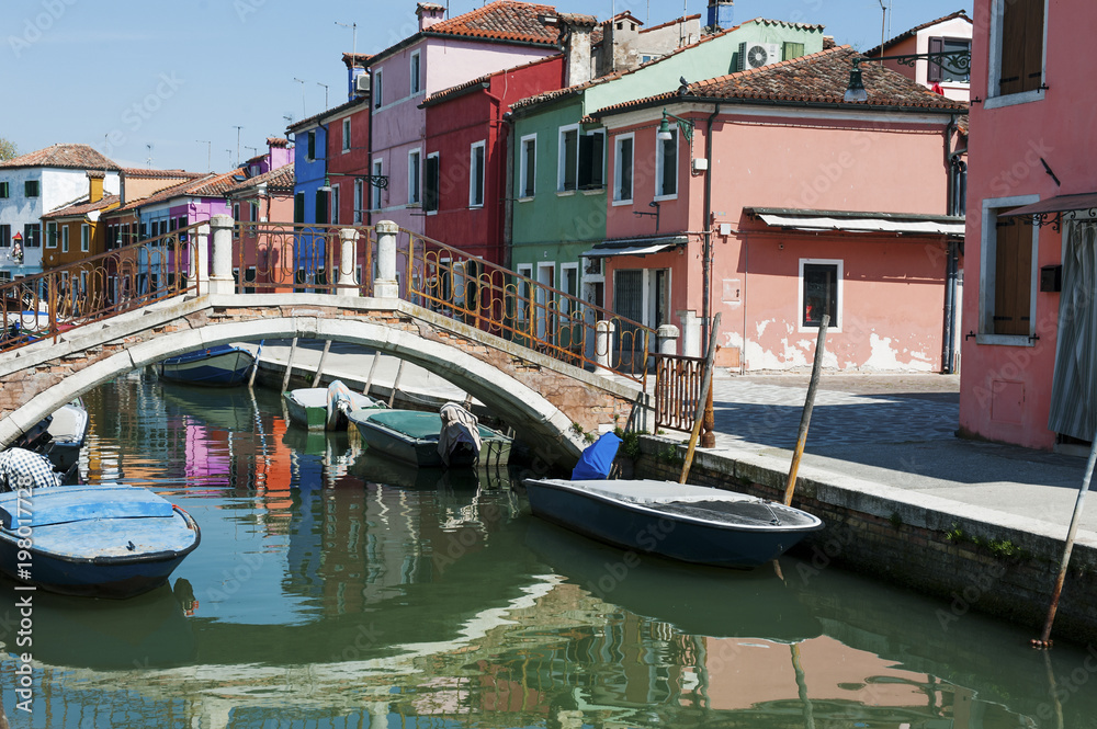 Burano island, Venice, Italy - view of canal, colorful houses, boats and a bridge
