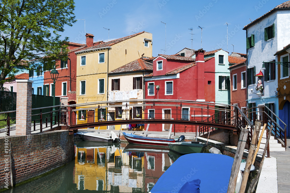 Brightly colorful houses reflected in the canal in Burano, a beautiful island in the Venetian lagoon near Venice, Italy