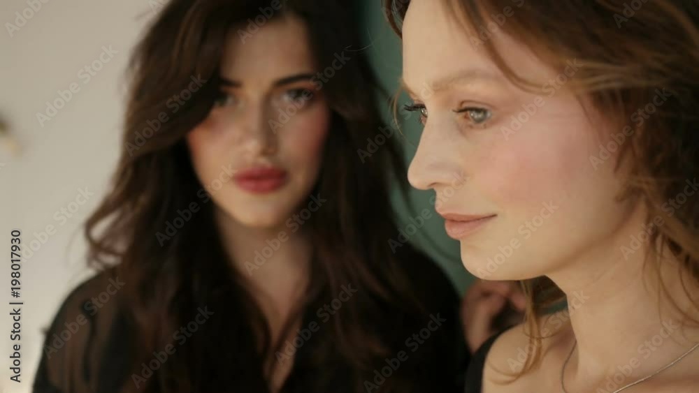 Two women are standing by the wall Two women are standing by the wall