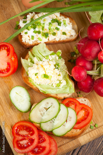 Summer sandwiches ingredients - cucumber, radish, tomato, mozzarella and eggs, white wood background, top view