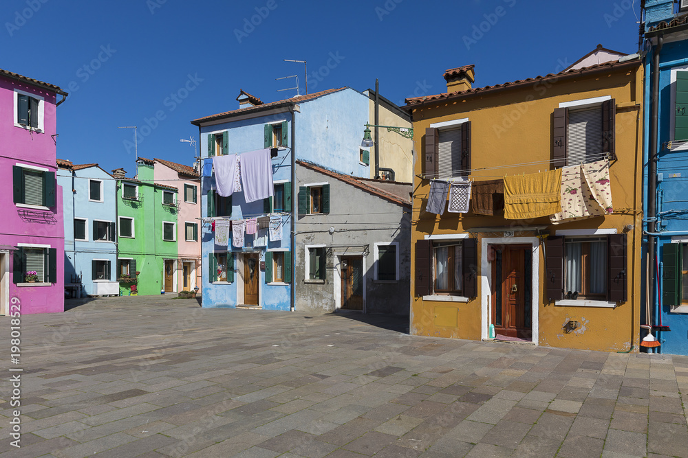 Colorful buildings with vibrant colors and laundry drying in famous fishermen village on the island of Burano, Venice, Italy