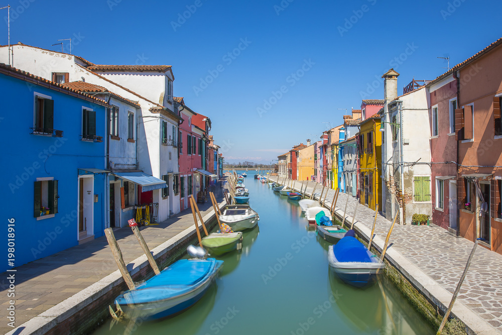 Typical canal with colorful facades with vibrant colors in famous fishermen village on the island of Burano, Venice, Italy