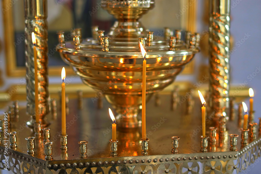 Church candle burns on the altar in front of the Orthodox icon