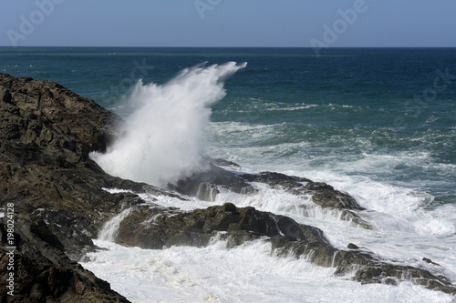 Hoch aufspritzende Gischt an einer  Felsenküste.