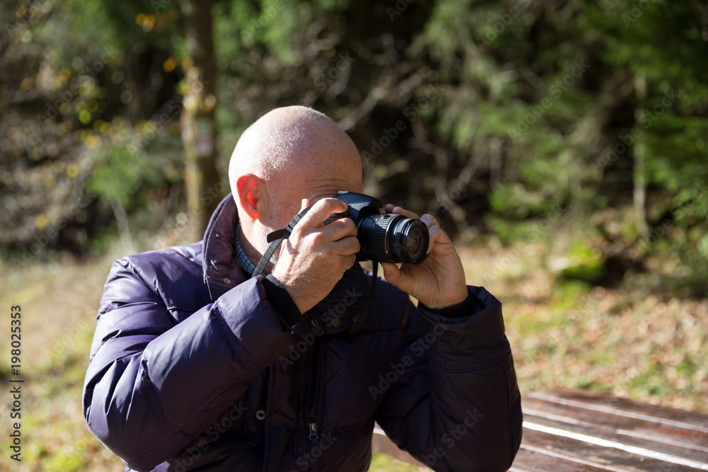 Bald mature man taking pictures with camera outdoors Bald mature man taking pictures with camera outdoors