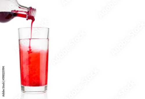 Pouring berry syrup  into water glass on white background photo