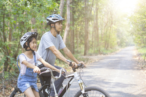 Happy father and daughter cycling in the park, togetherness relaxation concept