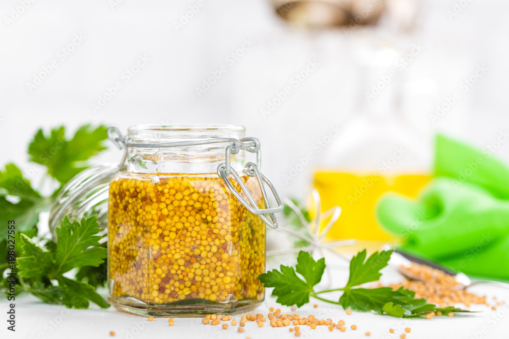 Mustard in glass jar on white wooden table closeup. Dijon mustard Mustard in glass jar on white wooden table closeup. Dijon mustard