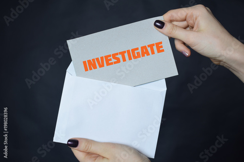 In the hands of a businessman an envelope with the inscription:INVESTIGATE