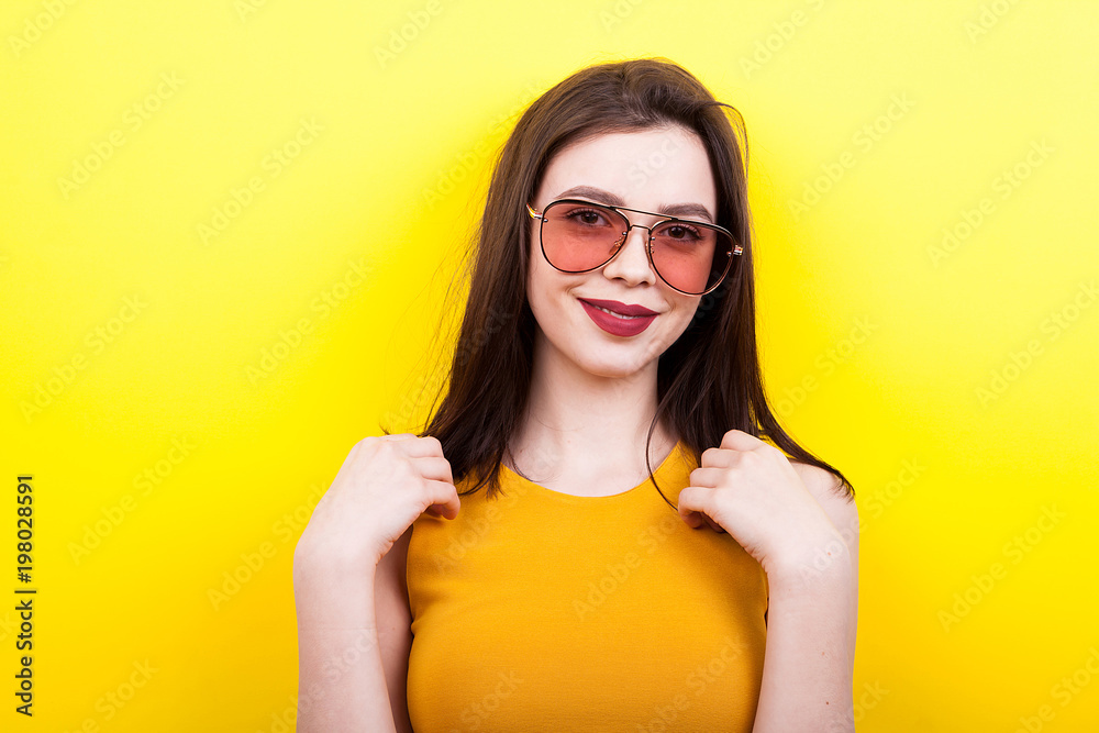 Smiling woman wearing sunglasses on yellow background Smiling woman wearing sunglasses on yellow background