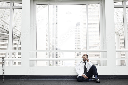 Black man doctor stressed out and sitting on floor. photo