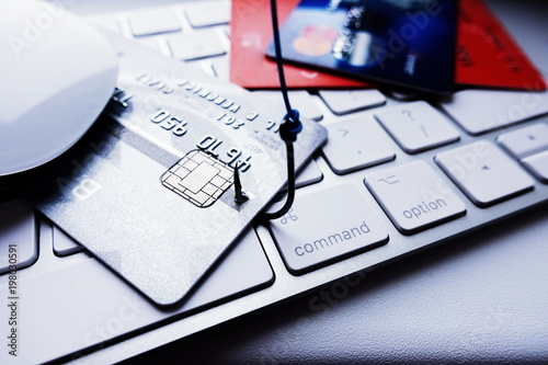 Credit card phishing attack concept, stealing credit card details with fishing hook on laptop keyboard
