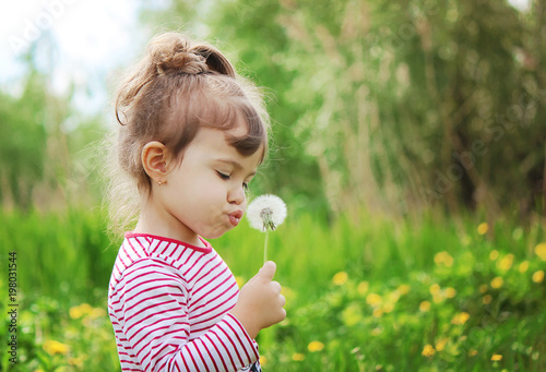 girl blowing dandelions in the air. selective focus. 