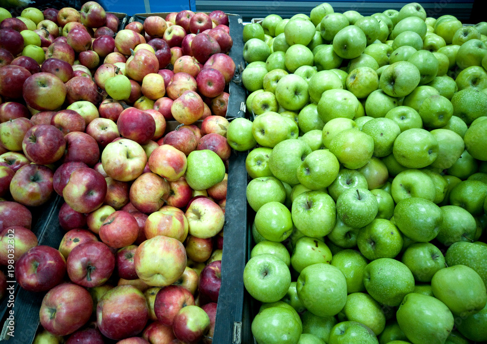 Fresh green and red apples lie in the shop window