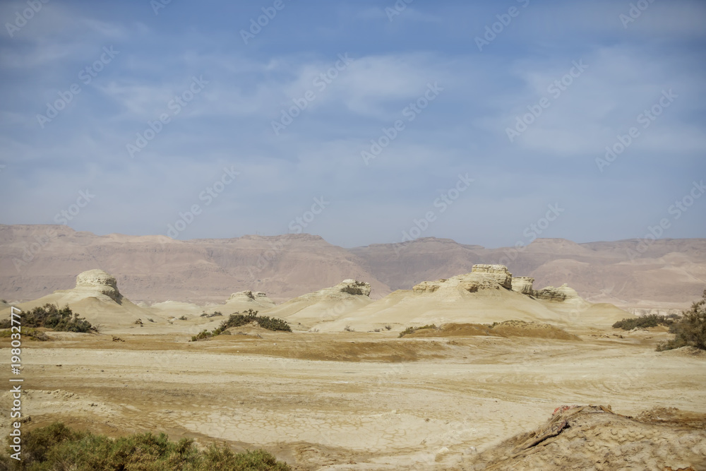 The old mountains of the Negev desert of different colors on the background of the blue sky with clouds