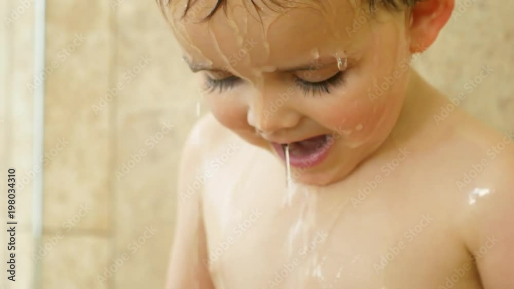 Slow motion of adorable toddler boy standing in a tile shower Slow motion of adorable toddler boy standing in a tile shower