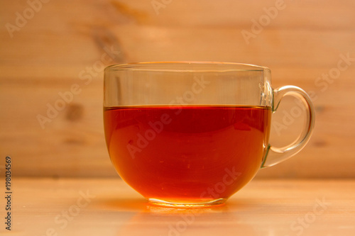 Transparent cup with tea on wooden background