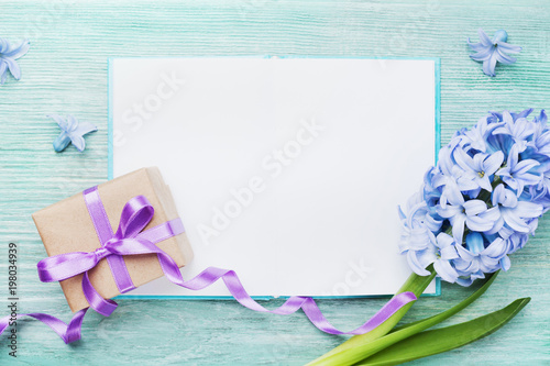 Mothers Day holiday card with empty notebook for greeting text, gift or present box and fresh flowers top view.