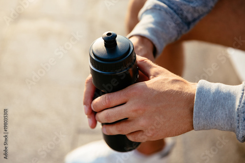 Close-up photo of male hands holding a bottle with water