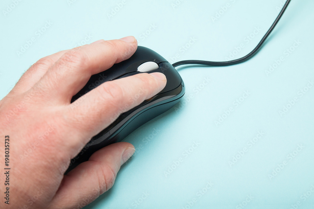 Hand and computer mouse on a blue background, empty space for text. Hand and computer mouse on a blue background, empty space for text.