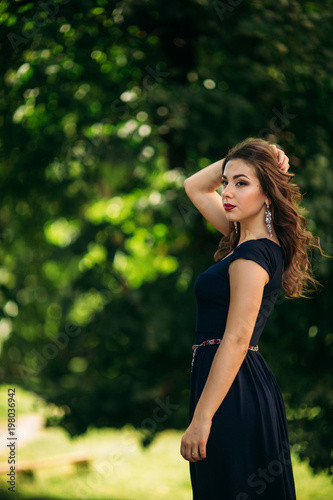 A beautiful girl in a blue dress is walking in the park.