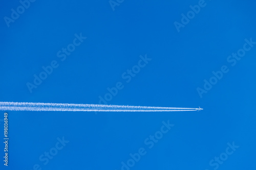 Condensation trace highlighted by the setting sun behind a twin-engine turbojet passenger plane in the March sky © klevo