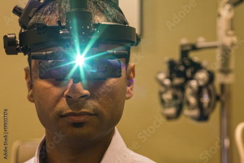 Ophthalmologist wearing a binocular indirect ophthalmoscope for examining eyes. photo