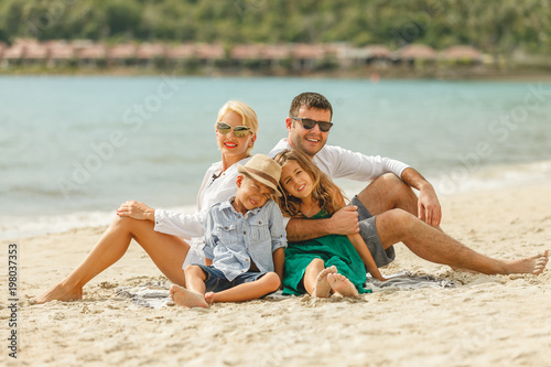 beautiful happy family sitting on beach on vacation