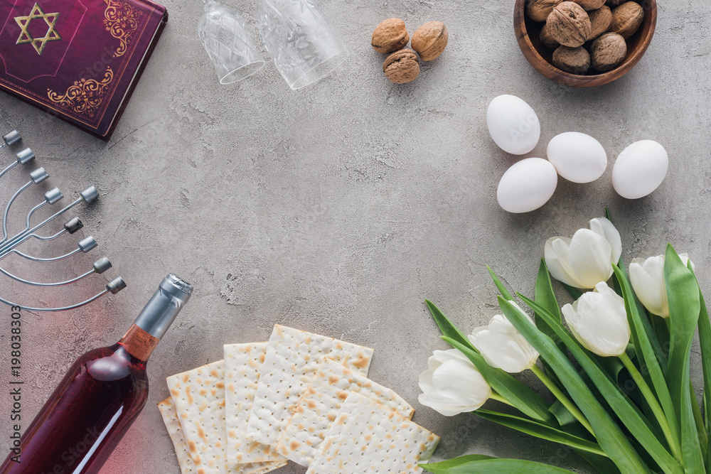 Top view of traditional book with text in Hebrew and matza on concrete table Top view of traditional book with text in Hebrew and matza on concrete table