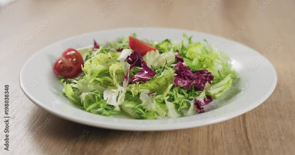man hand adding cherry tomatoes to salad leaves man hand adding cherry tomatoes to salad leaves