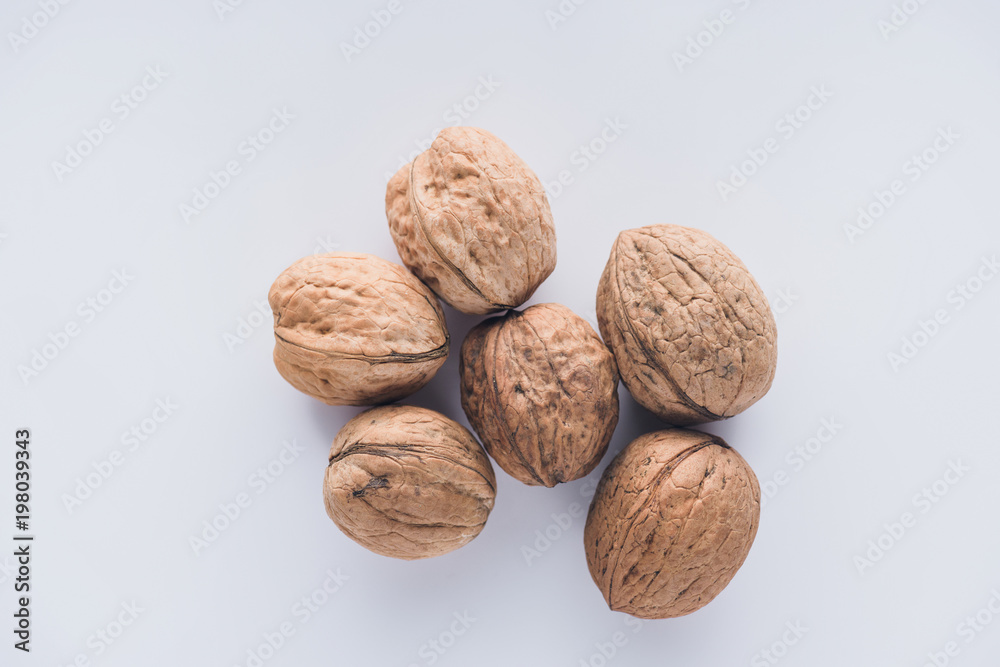 Top view of six walnuts on white surface Top view of six walnuts on white surface