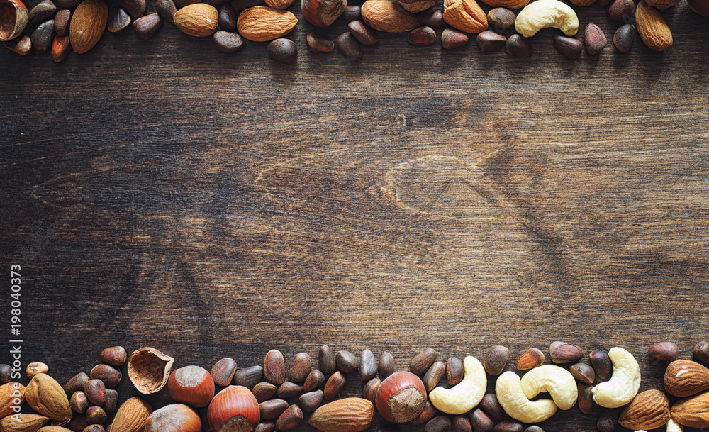 Different nuts on a wooden table. Cedar, cashew, hazelnut, walnu - obrazy, fototapety, plakaty 