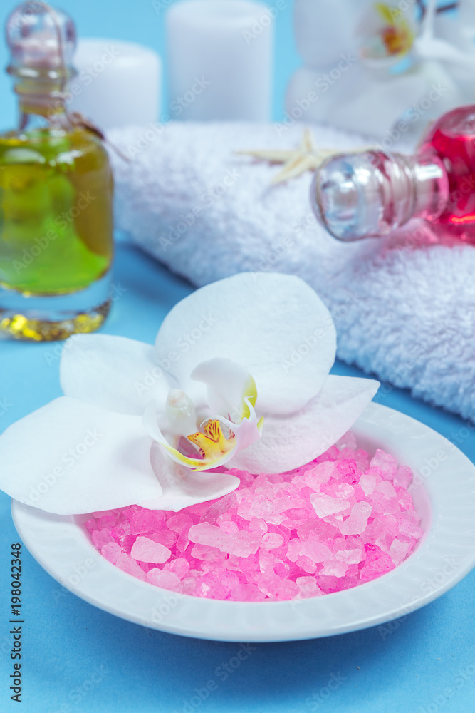 Spa background, flat layout with pink sea salt, candles and aroma oils and beauty care products on a blue background Spa background, flat layout with pink sea salt, candles and aroma oils and beauty care products on a blue background