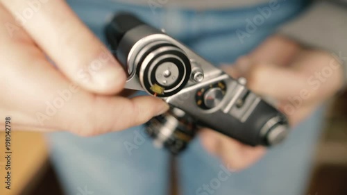 A young photographer changes shutter speed of a vintage old film camera and takes a picture.