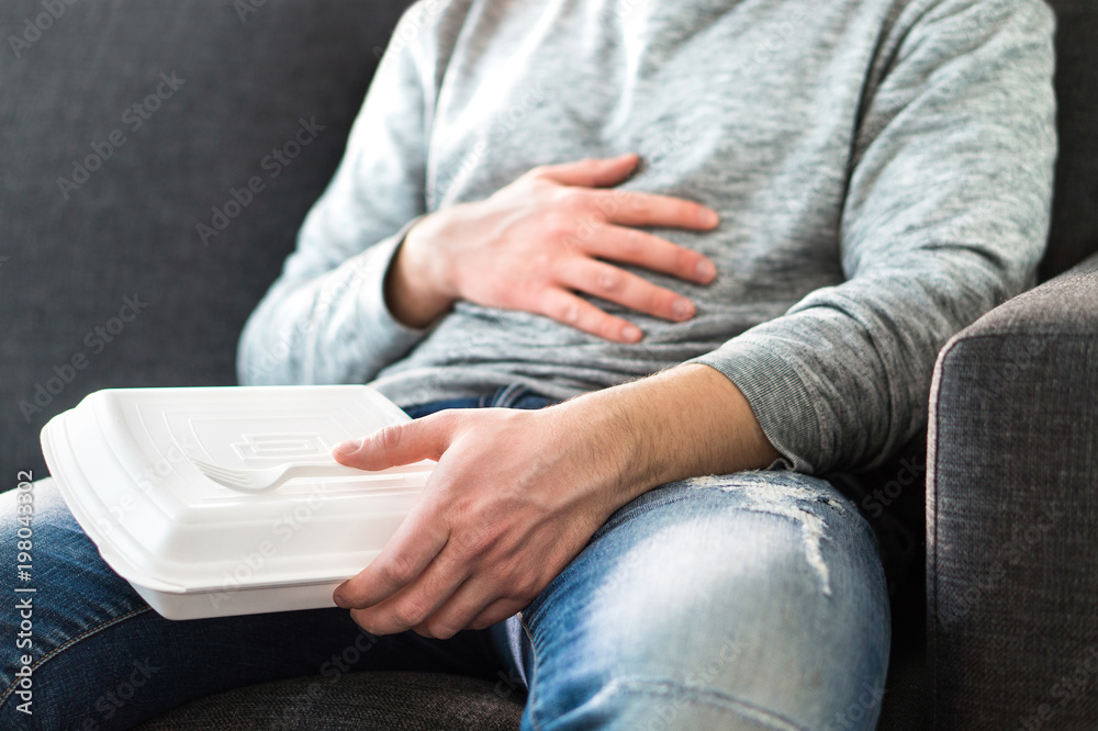 After eating fast food. Man feeling full or taking nap after eating junk. Guy having hangover or unhealthy diet. Stomach pain while sitting on couch. After eating fast food. Man feeling full or taking nap after eating junk. Guy having hangover or unhealthy diet. Stomach pain while sitting on couch.