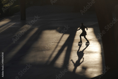 Silueta y sombra de una mujer patinando a última hora de la tarde en una pista urbana photo