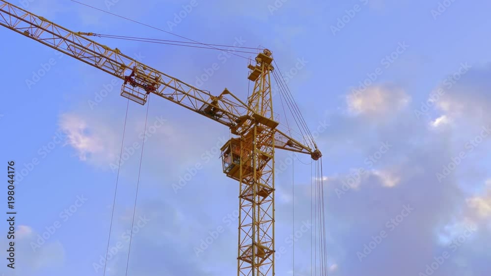 Tower crane / Crane building / Construction site. High tower crane working on the background of the summer sky with clouds. Tower crane / Crane building / Construction site. High tower crane working on the background of the summer sky with clouds.