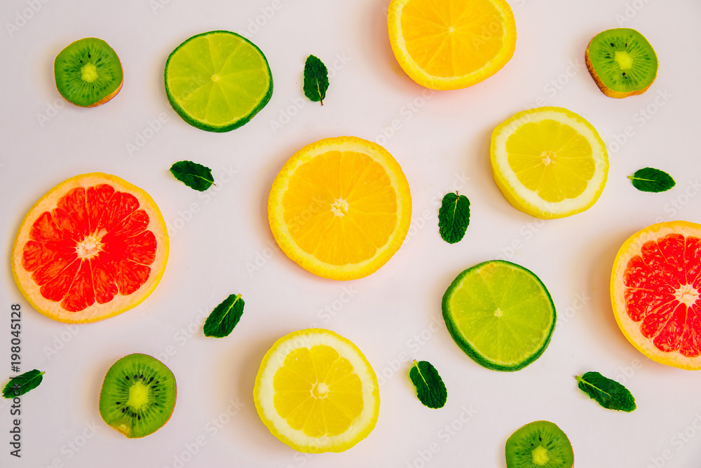 Fruit summer pattern on a white background. Slices of orange, lemon, kiwi, grapefruit and mint leaves. View from above Fruit summer pattern on a white background. Slices of orange, lemon, kiwi, grapefruit and mint leaves. View from above