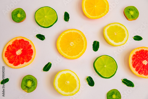 Fruit summer pattern on a white background. Slices of orange, lemon, kiwi, grapefruit and mint leaves. View from above