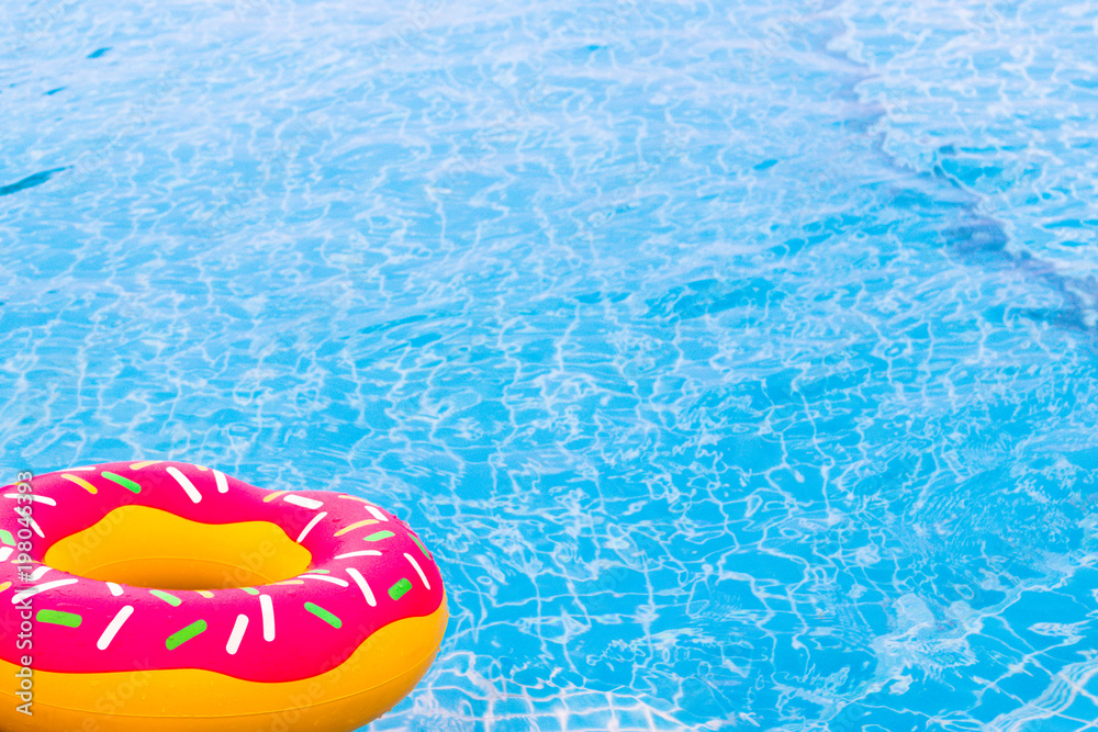 Swimming rubber ring with pink donut design above the pool